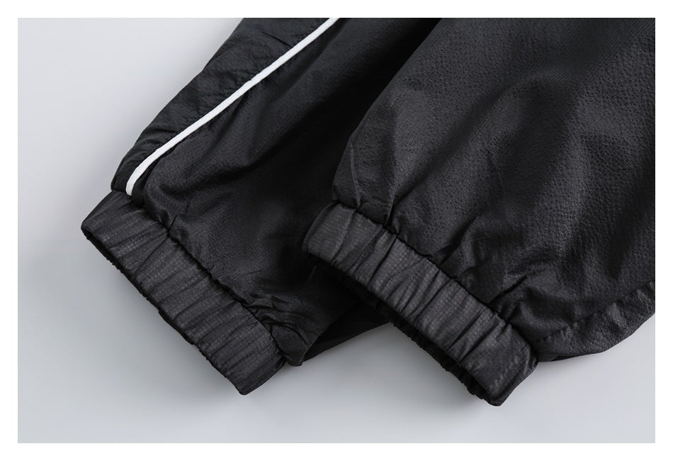 Close-up of black jacket cuffs with gathered elastic and a white piping detail.
