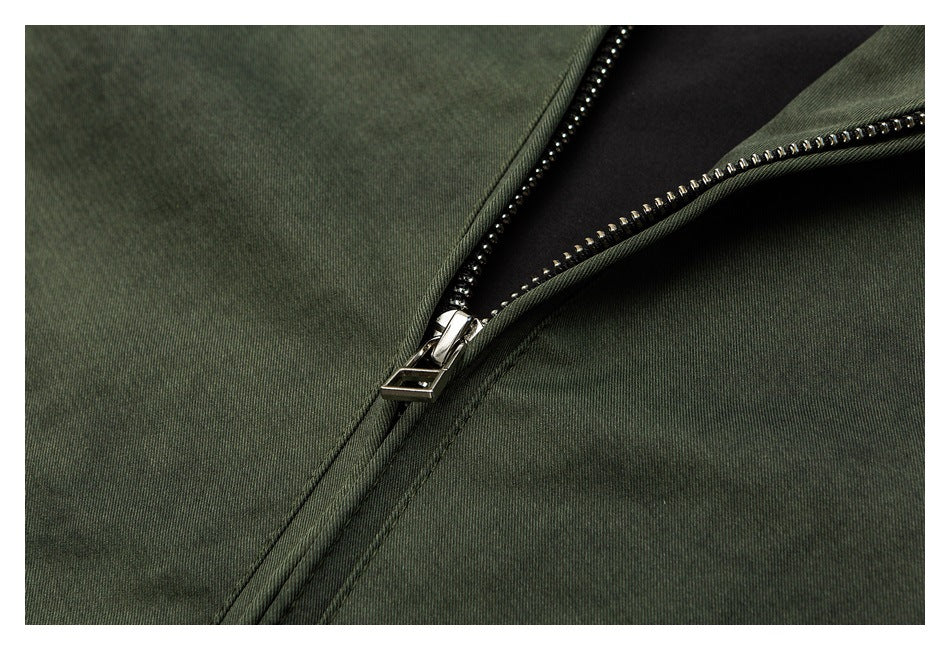 Close-up of an open silver-toothed zipper on dark olive fabric, revealing black lining.