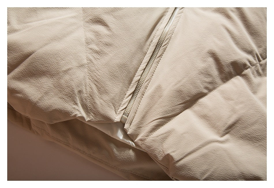 Close-up of the beige jacket's front zipper and lower panel seams.