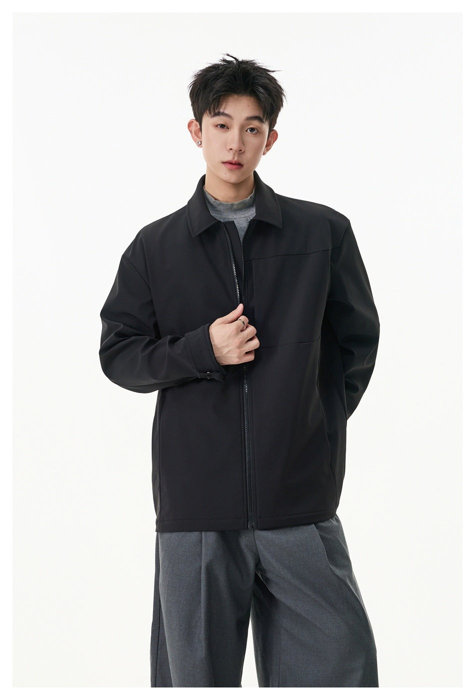 Model wearing a black zip-front jacket with a pointed collar and buttoned cuffs.