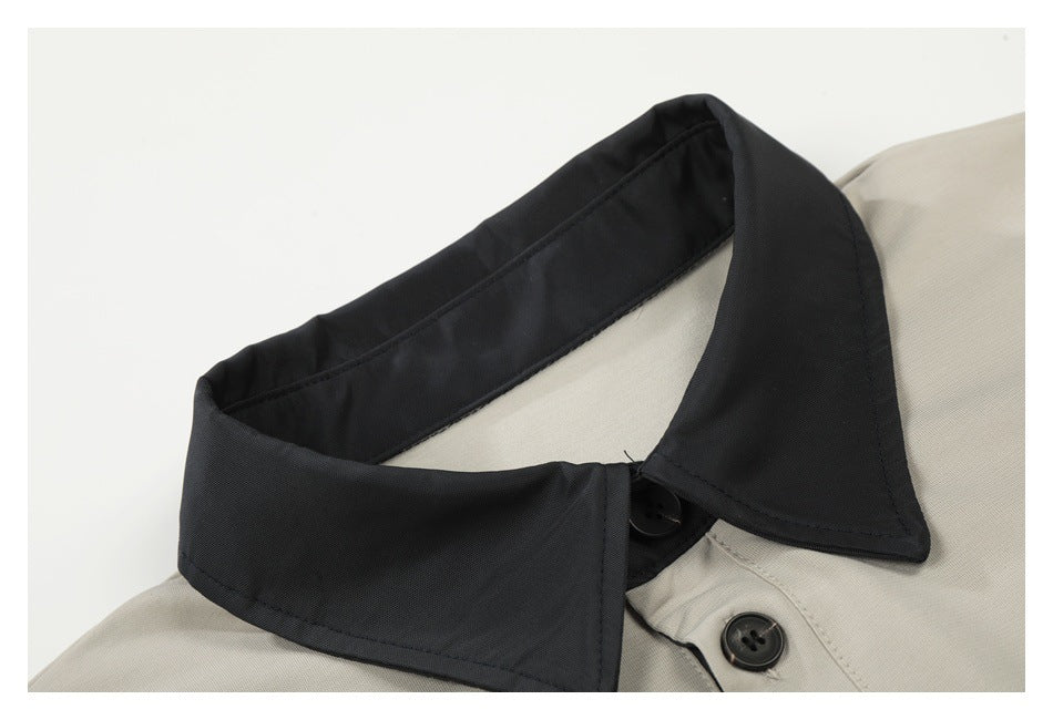 Close-up of the polo's black collar and upper placket on light beige fabric.