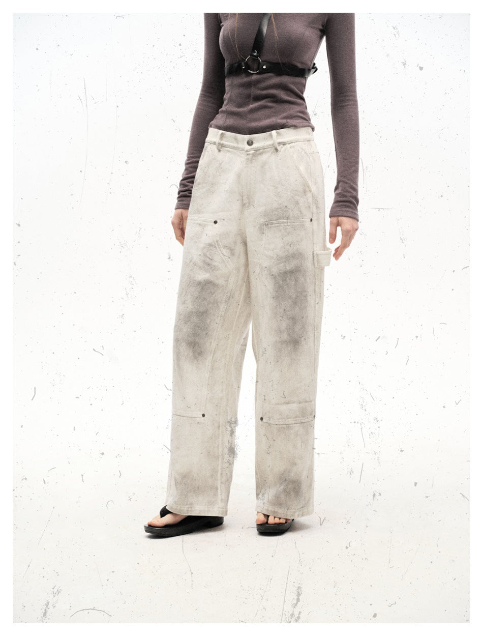 Cropped model view of distressed off-white wide-leg pants showing pockets, knee panels and hammer loop