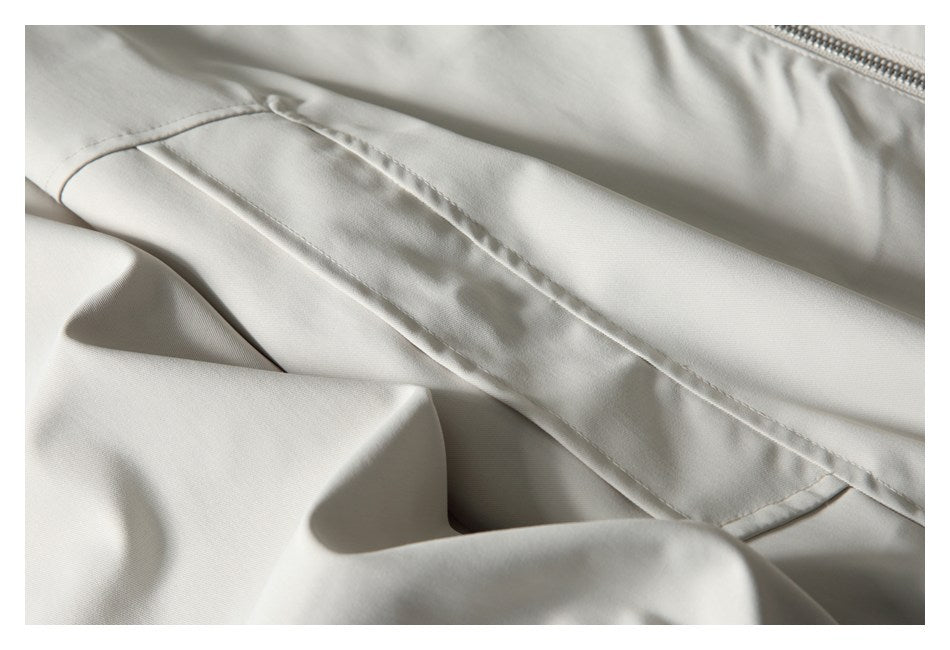 Close-up of an off-white garment with a stitched flap seam and a metal zipper.