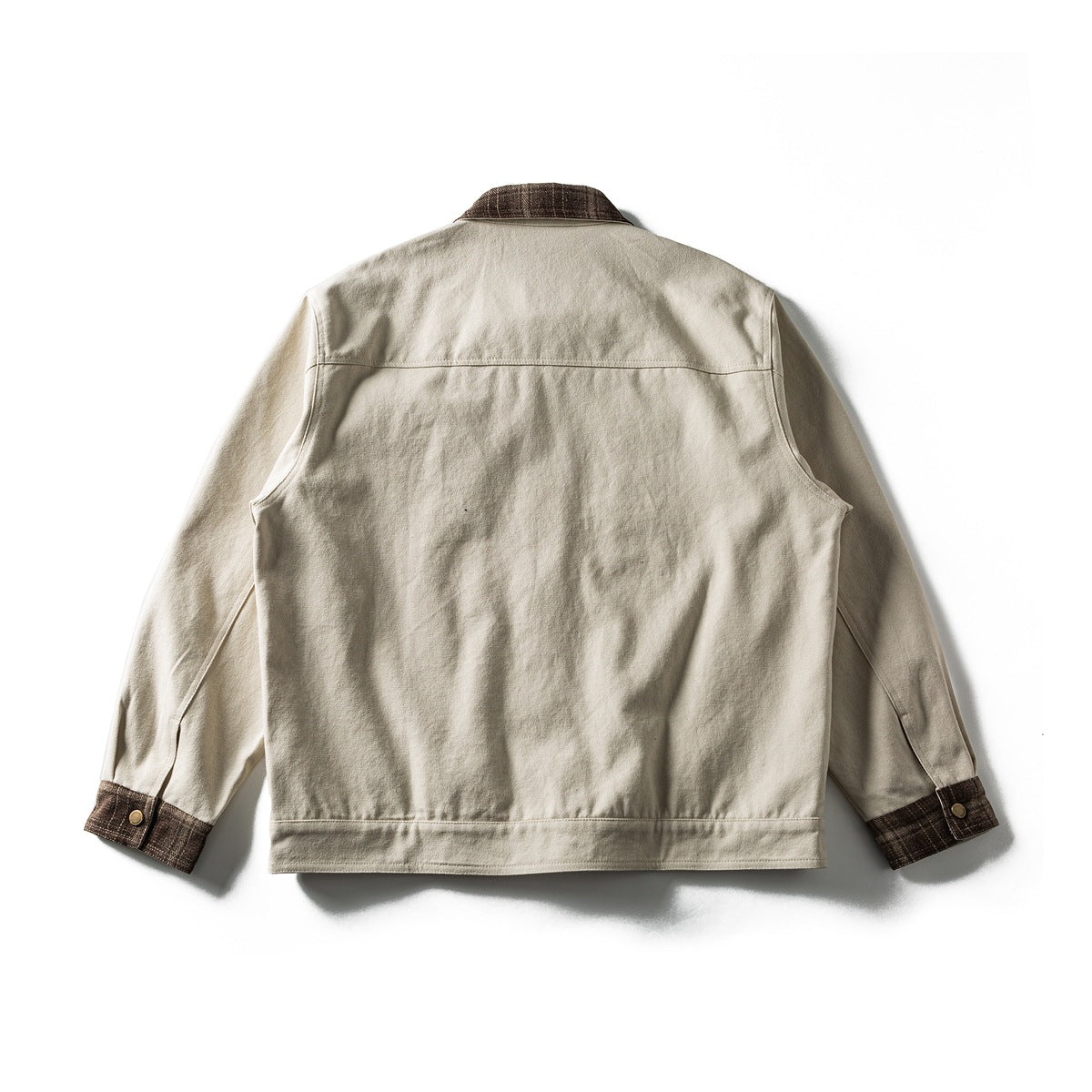 Back view of off-white jacket with brown plaid collar and cuffs, back yoke seam and waistband, laid flat