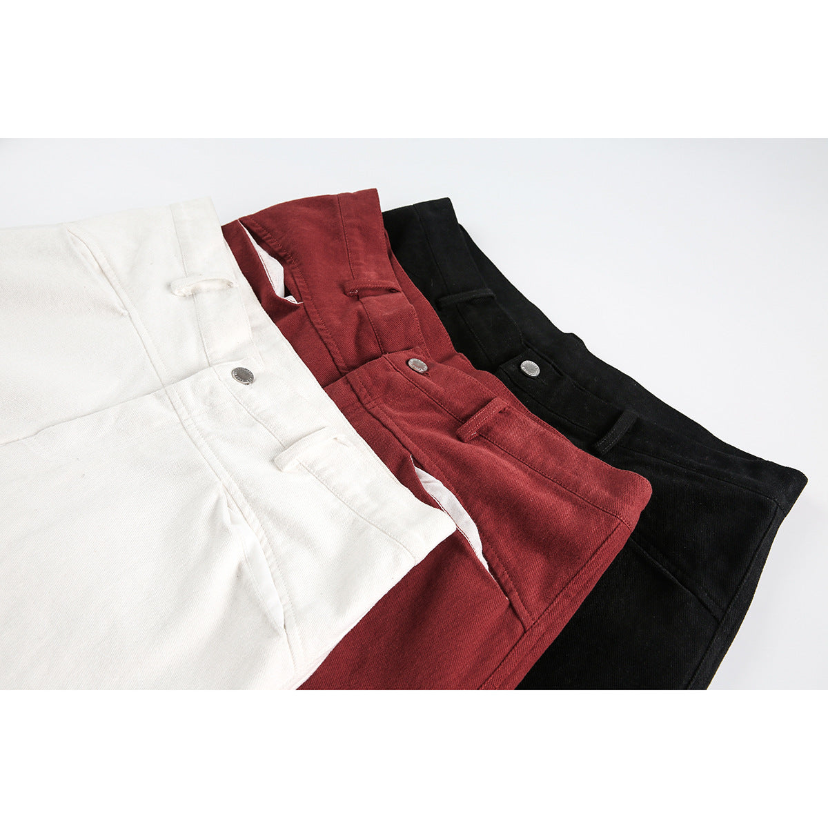 Close-up of white, burgundy, and black shorts showing waistbands, belt loops, and metal buttons.
