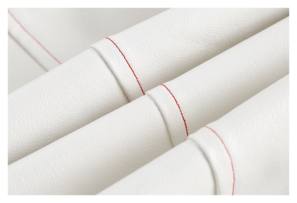Close-up of folded white garment panels with red seam stitching and a pebbled surface.