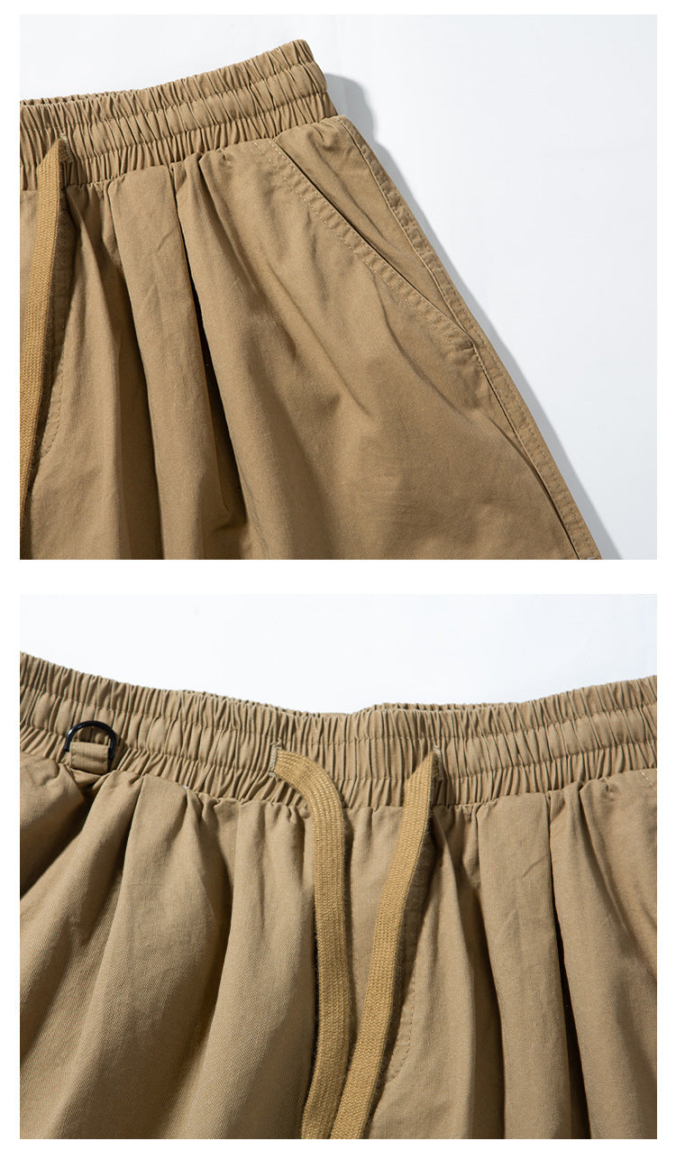 Close-up of tan cargo pants showing the elastic waistband, drawstring, and angled side pocket.