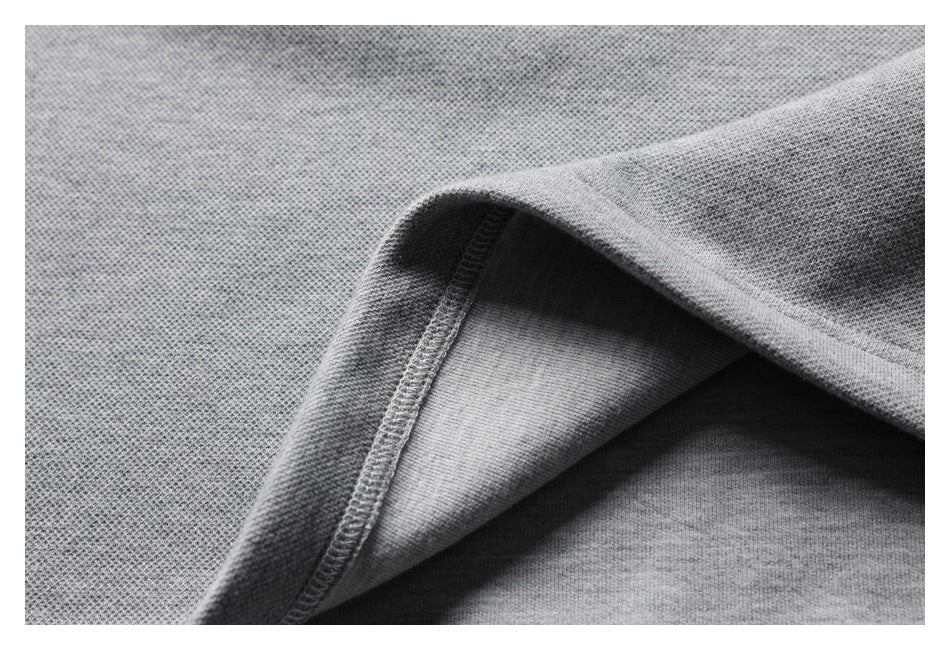 Close-up of a gray garment's folded seam and visible overlock stitching.