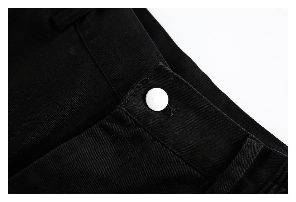 Close-up of black trousers showing a silver button at the waistband.
