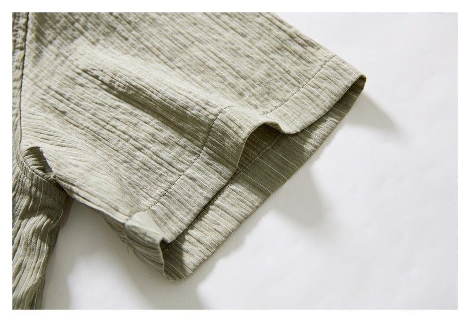 Close-up of the muted olive-gray shirt's striped sleeve cuff and stitched hem.