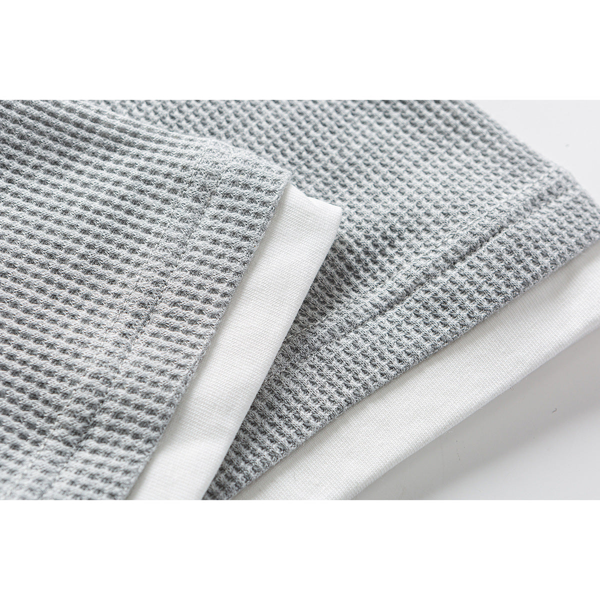 Close-up of gray textured polo fabric and white contrast hem trim.