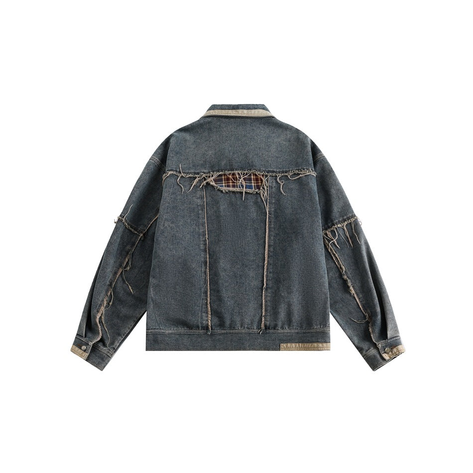 Back view of a dark blue denim jacket with frayed seams, plaid inserts, and a light contrasting collar.