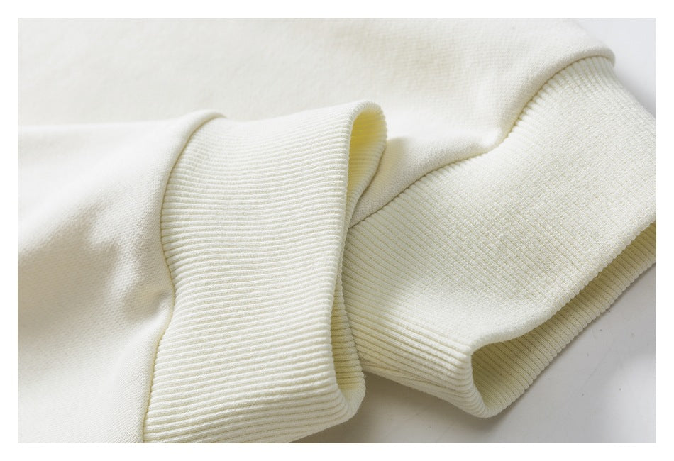 Close-up of the cream sweatshirt’s ribbed sleeve cuff and hem.