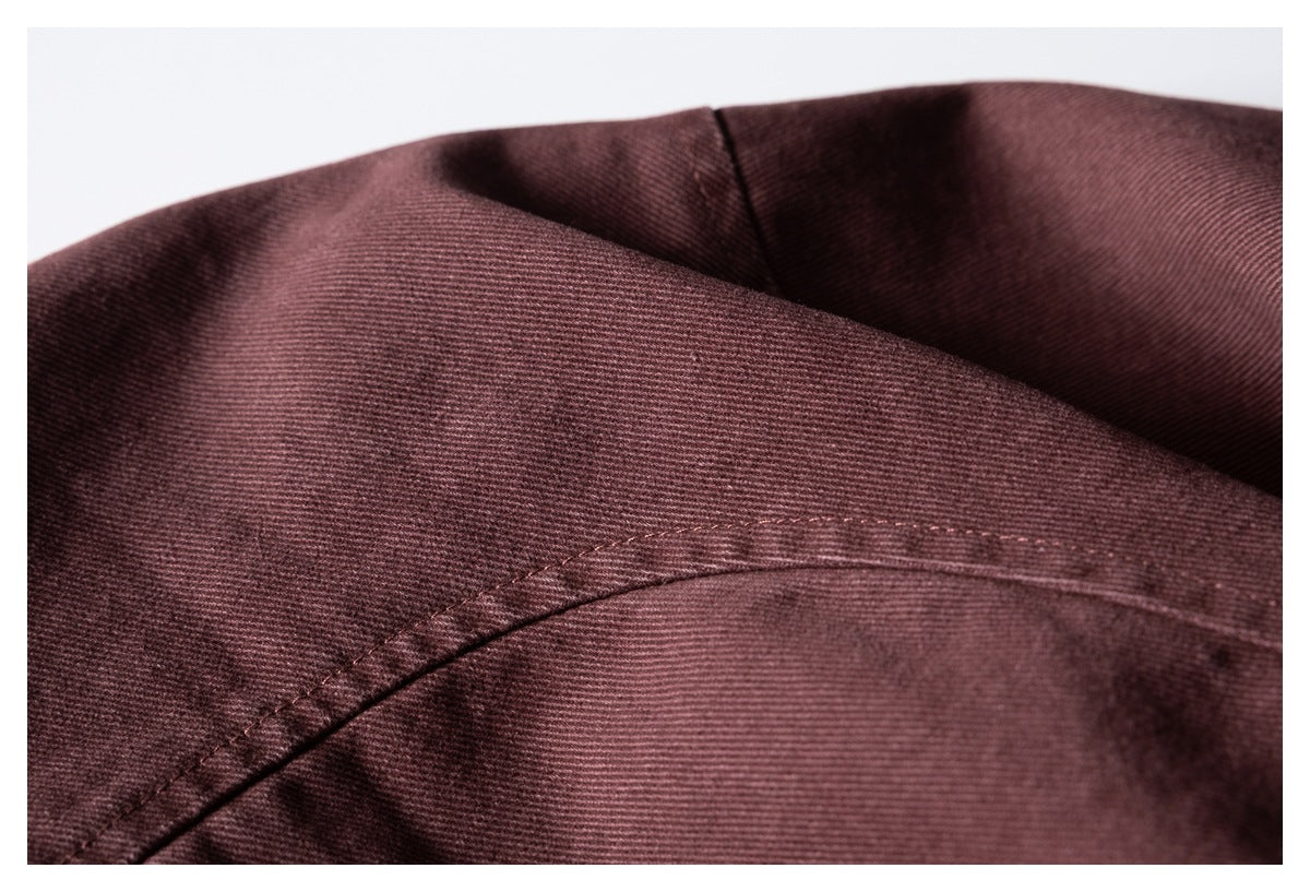 Close-up of a curved stitched seam on burgundy fabric.