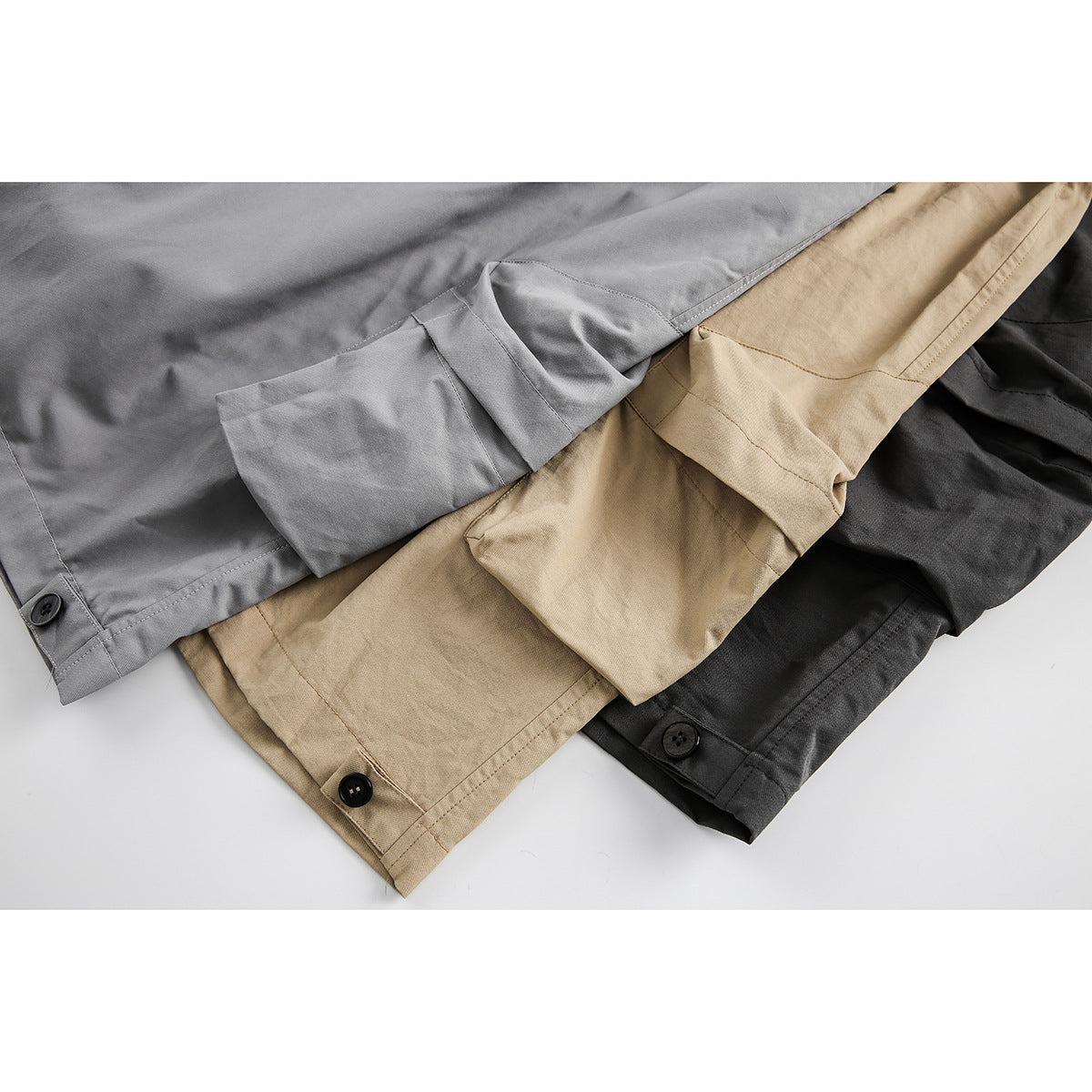 Close-up of gray, tan, and charcoal shorts showing hems, seams, and button details.
