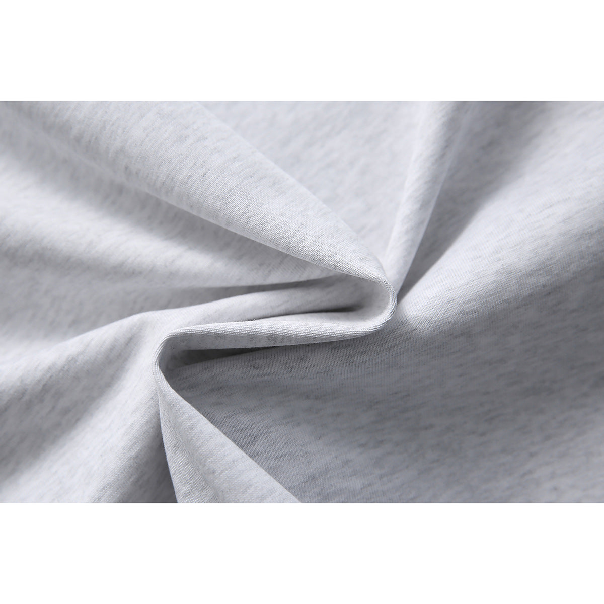 Macro view of light gray heather T-shirt fabric draped into soft folds.