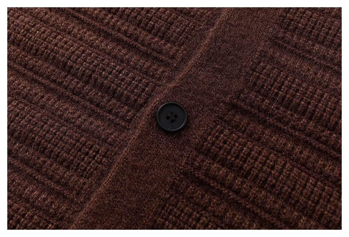 Close-up of a black button on a brown textured knit cardigan.