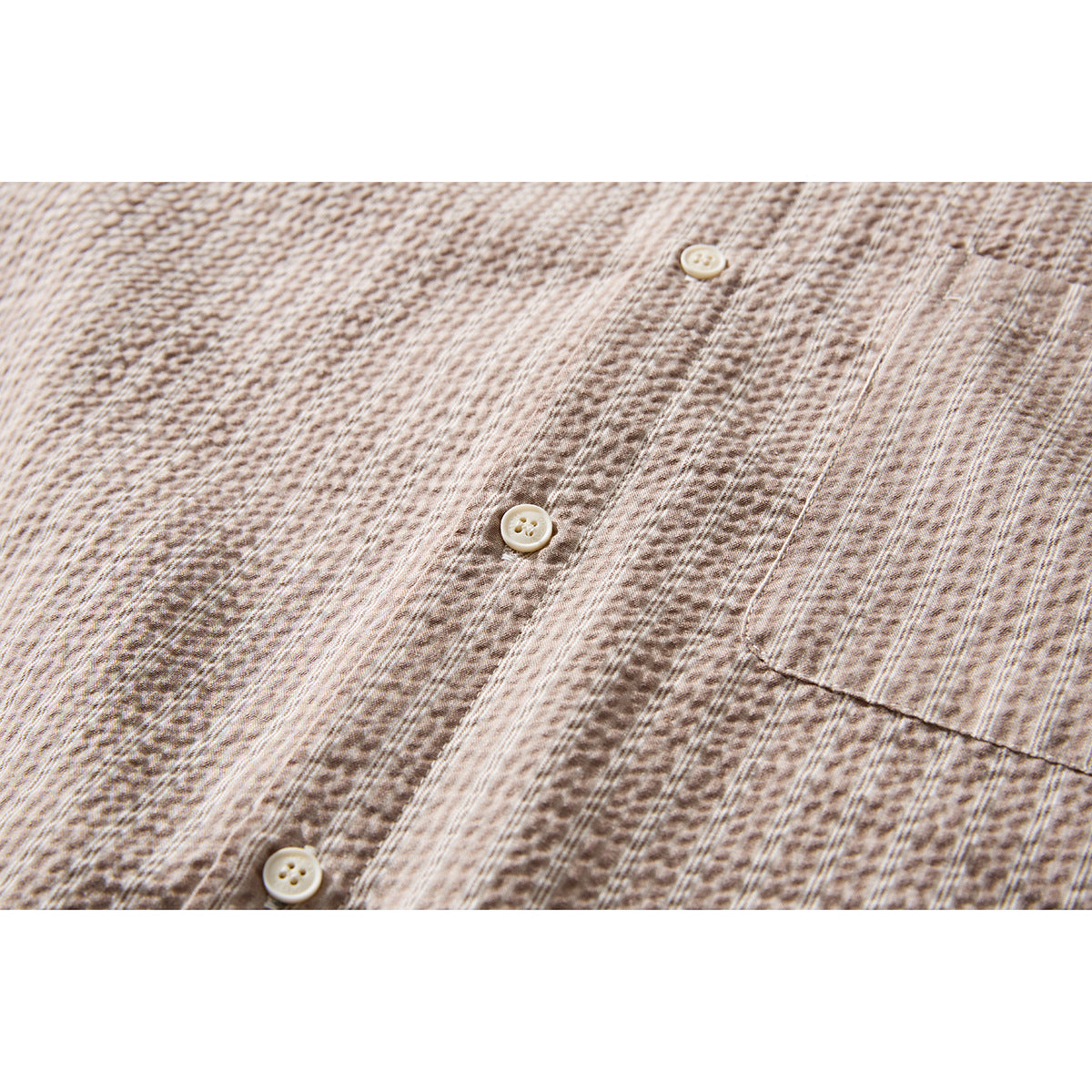 Close-up of a beige-brown textured shirt front with cream buttons and a chest pocket.