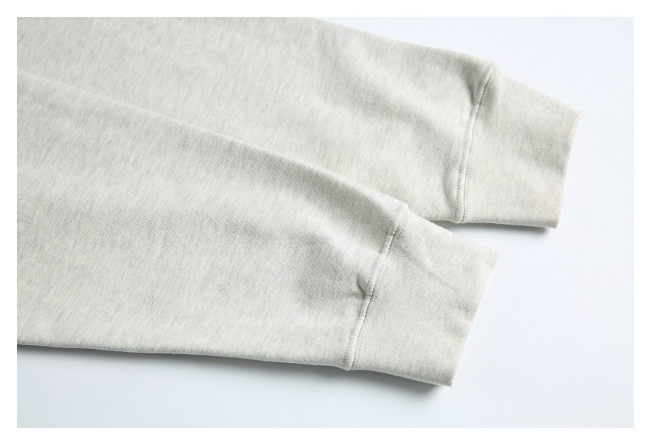Close-up of two light gray sweatshirt sleeves ending in wide ribbed cuffs.