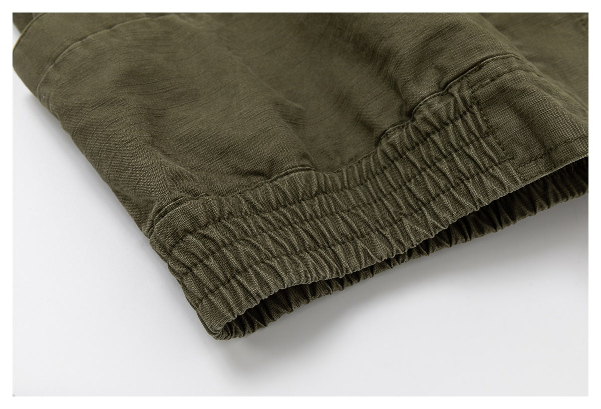 Close-up of an olive drab garment's gathered elastic hem and stitched seam.