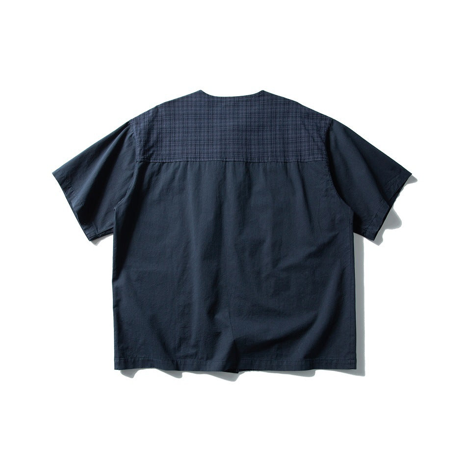 Back view of navy blue short-sleeve shirt with a plaid yoke across the upper back and solid lower back, flat lay