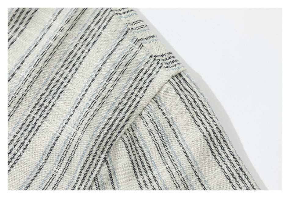 Close-up of intersecting seams on a cream garment with black and pale blue stripes.