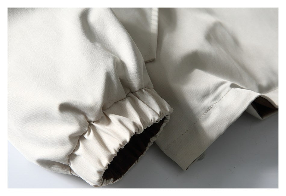 Close-up of the ivory jacket's gathered elastic cuff and stitched sleeve hem.