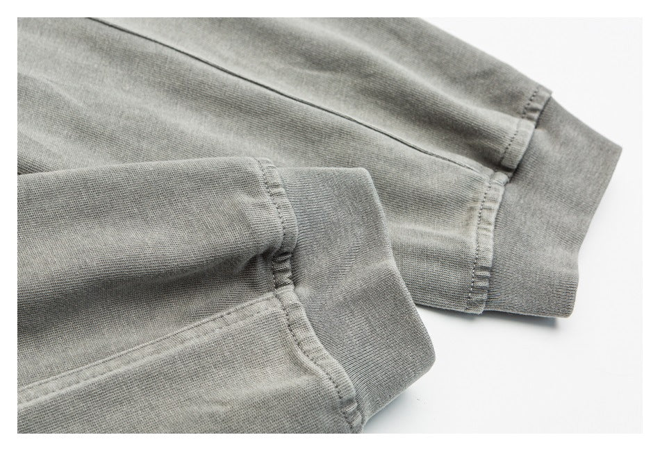 Close-up of two ribbed cuffs and stitched seams on a gray garment.