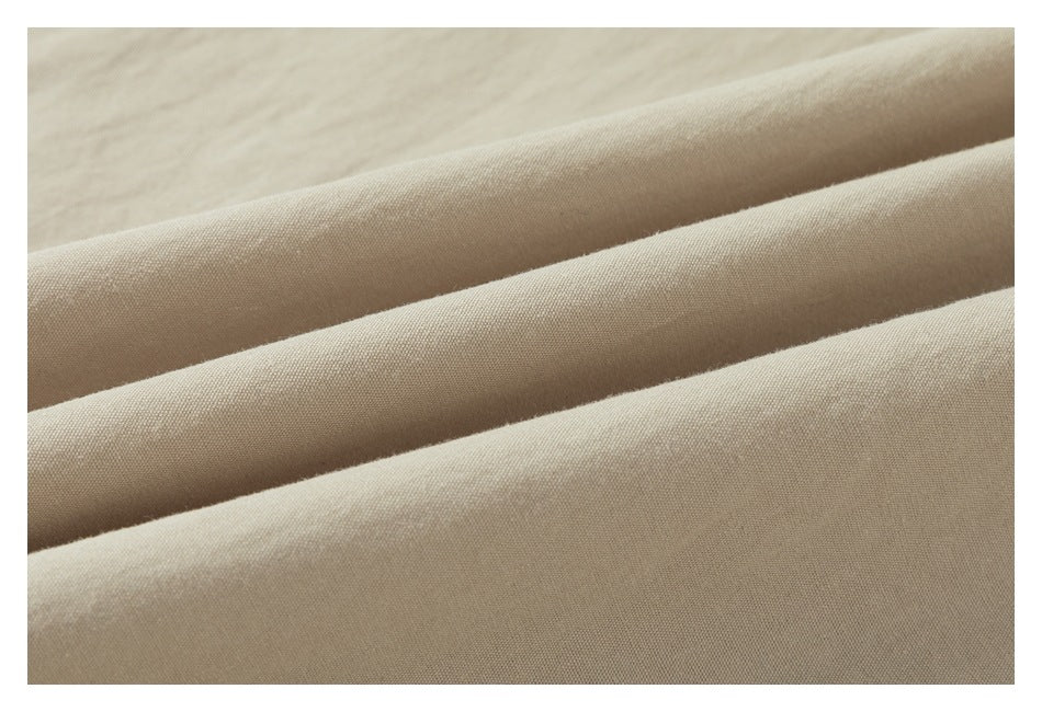 Close-up of beige fabric arranged in soft diagonal folds, showing its fine surface texture.