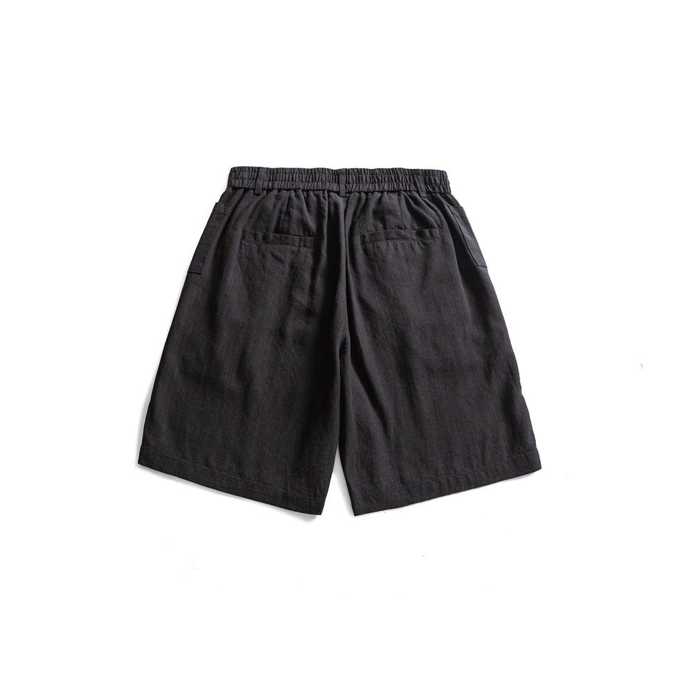 Back view of black shorts laid flat, with a gathered waistband and two rear pockets.