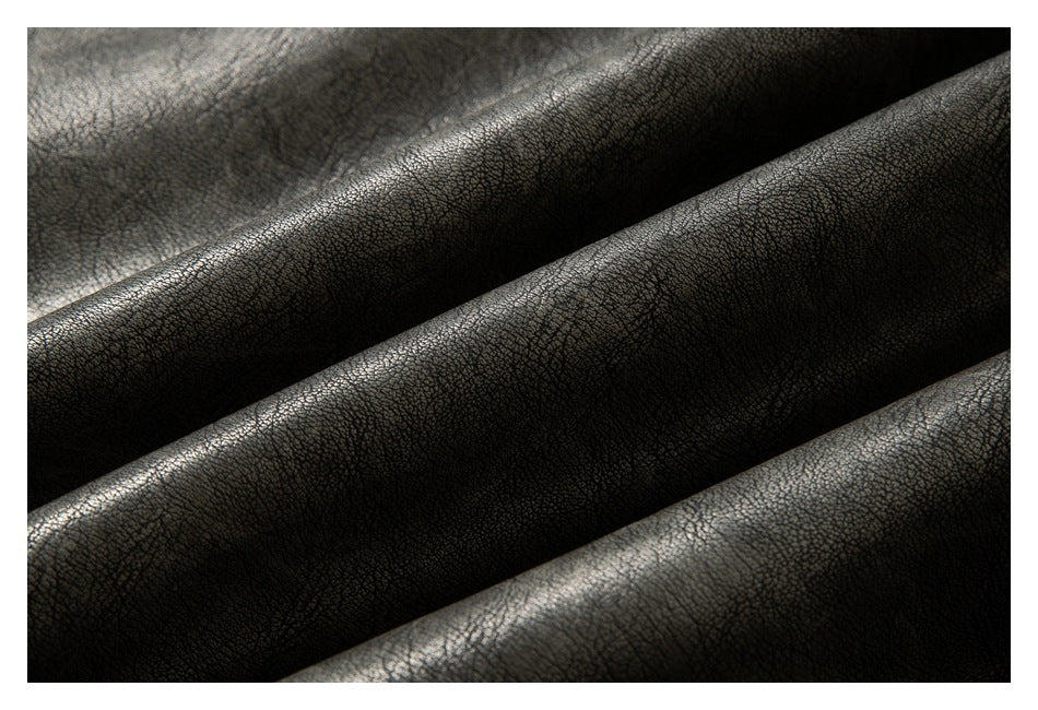 Close-up of dark charcoal, pebbled material folded into diagonal ridges with a subtle sheen.
