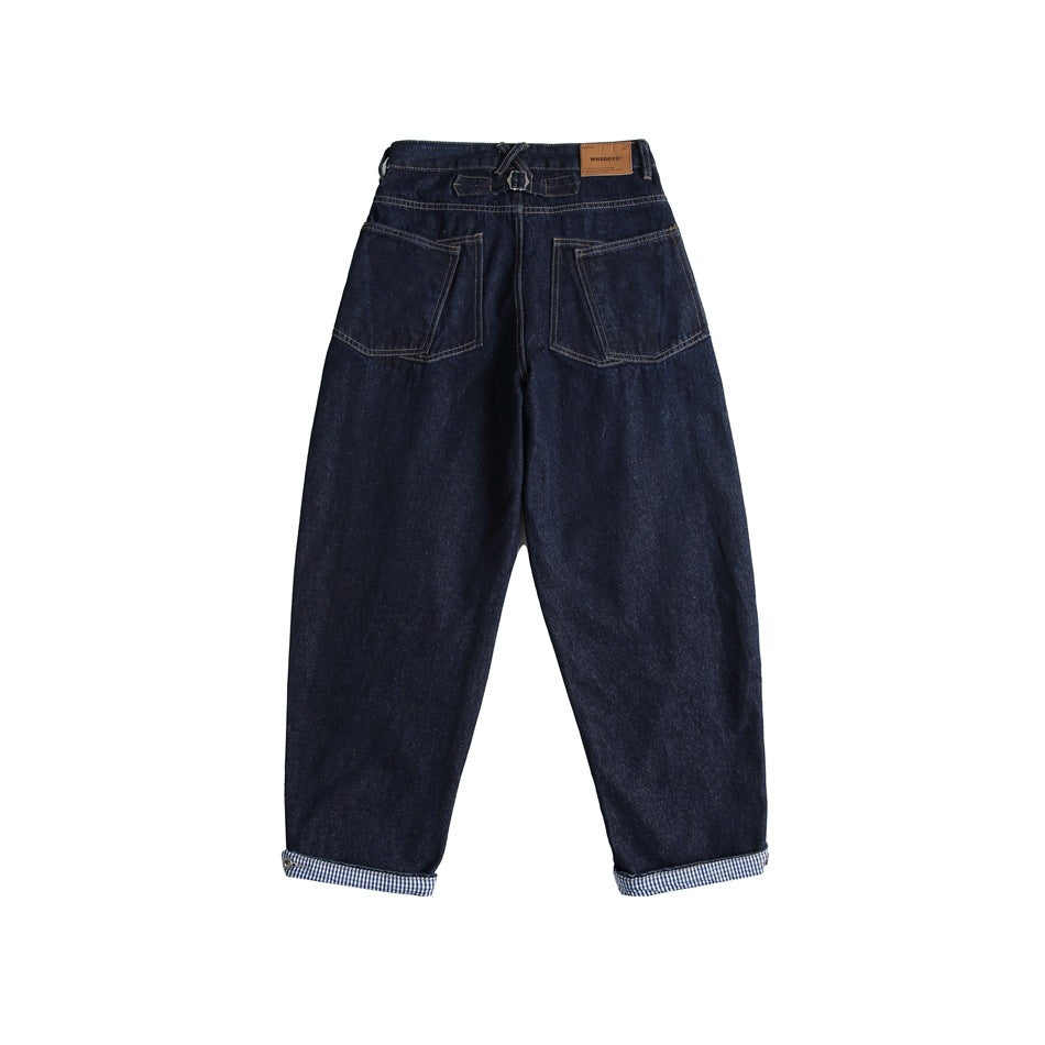Back view of dark navy jeans with two patch pockets, buckle strap at the waist and gingham-lined rolled cuffs