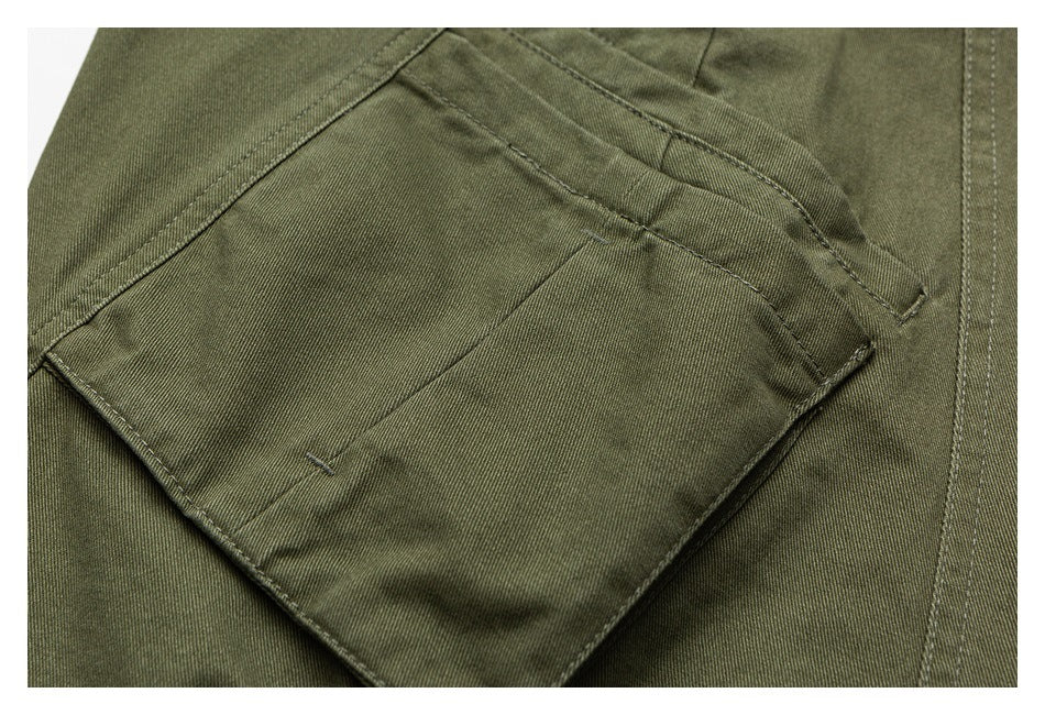 Close-up of an olive-green trouser cargo pocket with a flap and stitched edges.