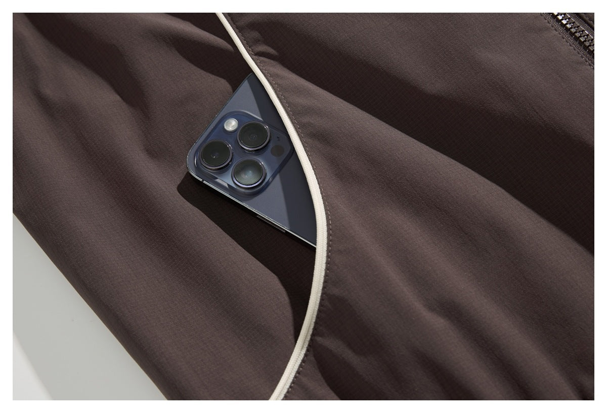 A phone tucked into a pocket of dark brown fabric edged with cream piping.