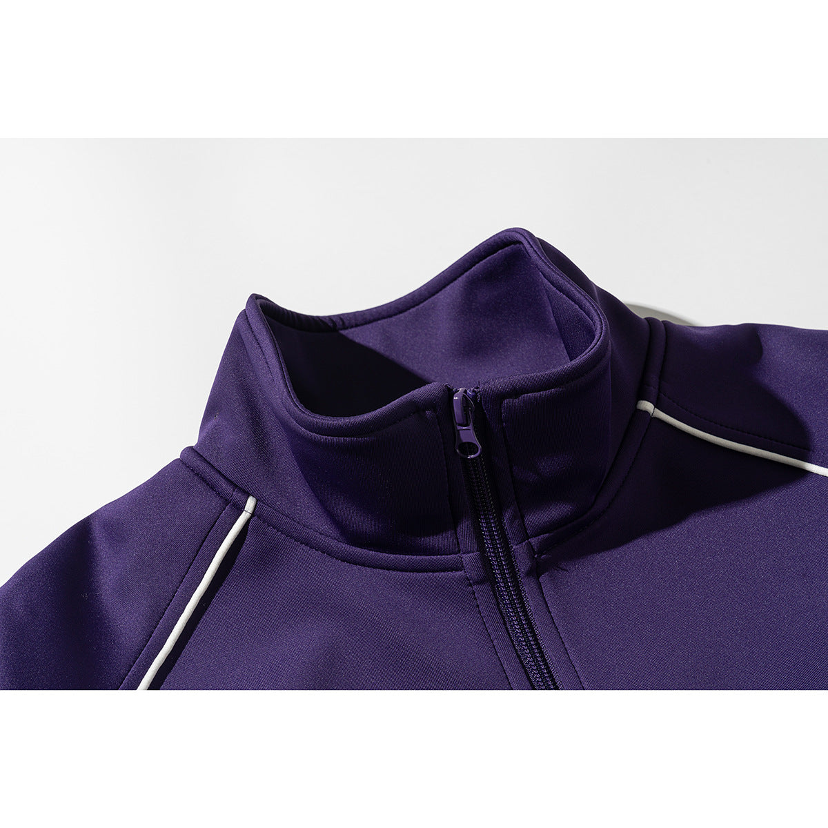 Close-up of a purple jacket's stand collar, front zipper, and white shoulder piping.