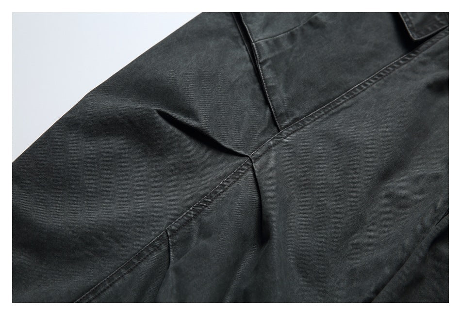 Close-up of charcoal pants showing the crotch seam and stitched fabric panels.