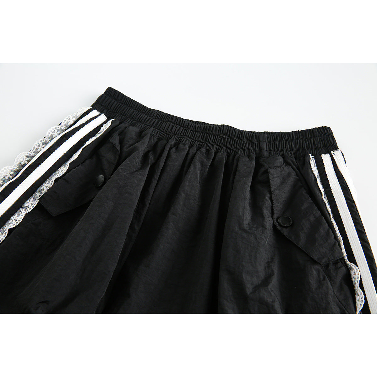 Close-up of the black skirt's gathered elastic waistband, buttoned flap pockets, white stripes, and lace edging.