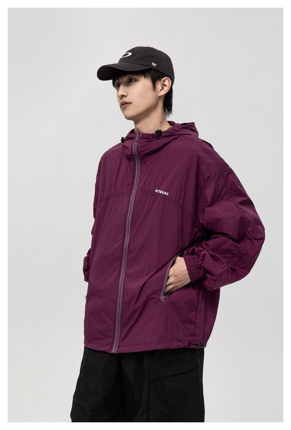Three-quarter view of a model wearing a burgundy hooded zip jacket with zip pockets.