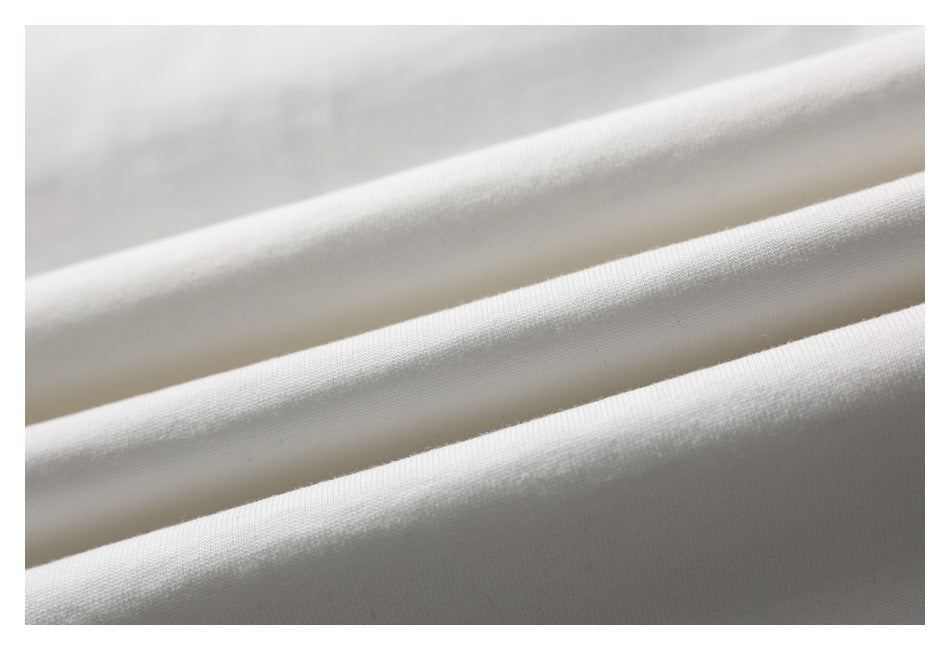 Close-up of white garment fabric arranged in soft folds, showing its surface texture.