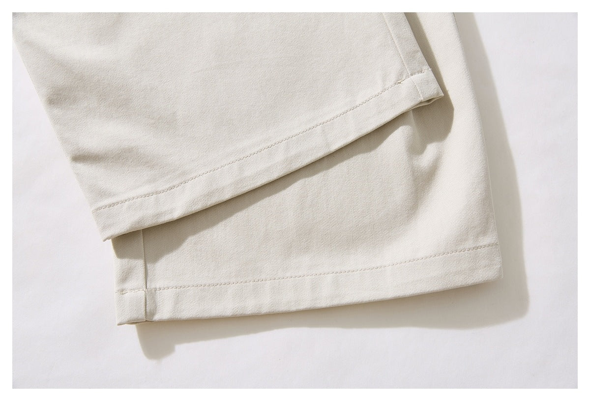 Close-up of the stitched hems on the cream trouser legs.