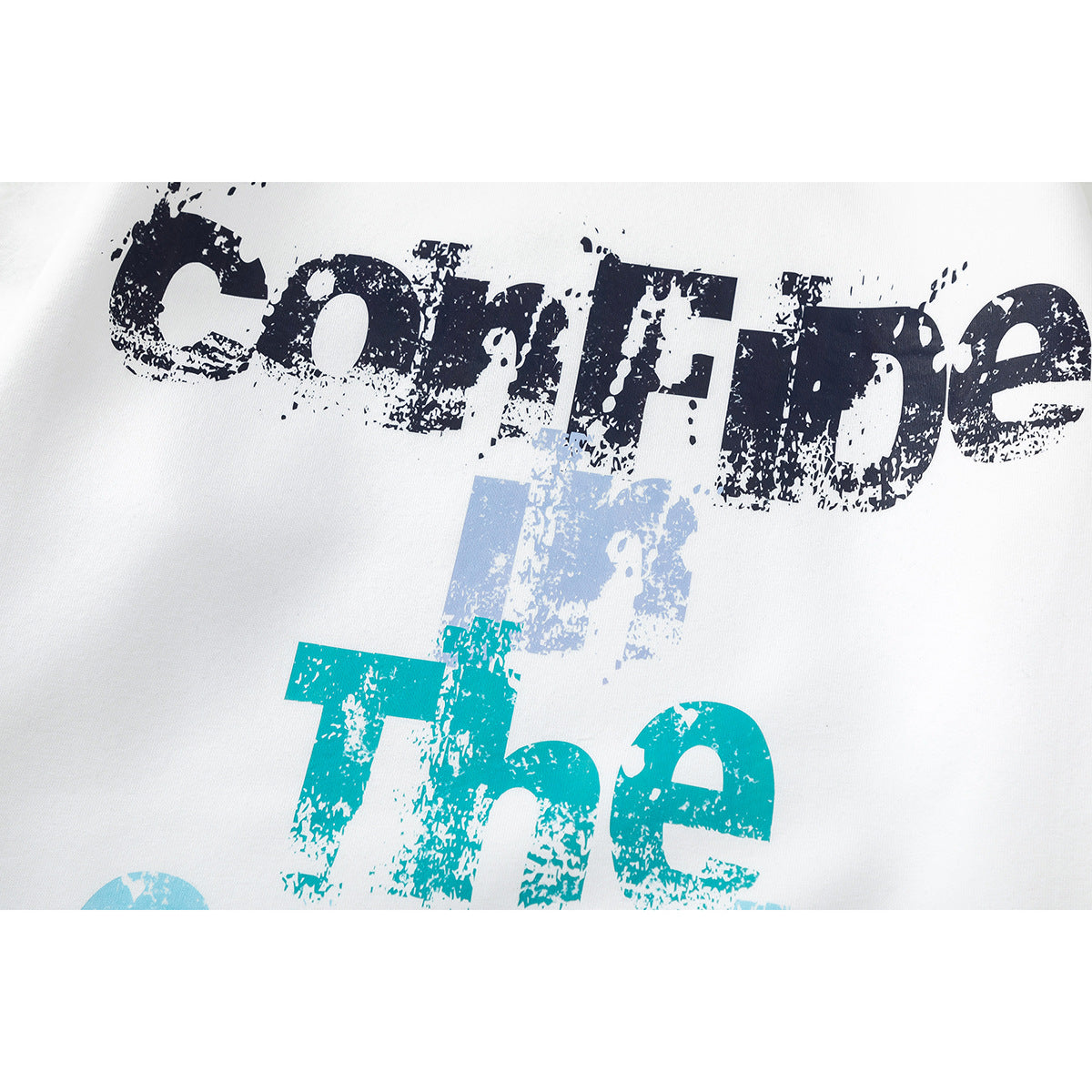 Close-up of distressed navy and turquoise lettering printed on white sweatshirt fabric.