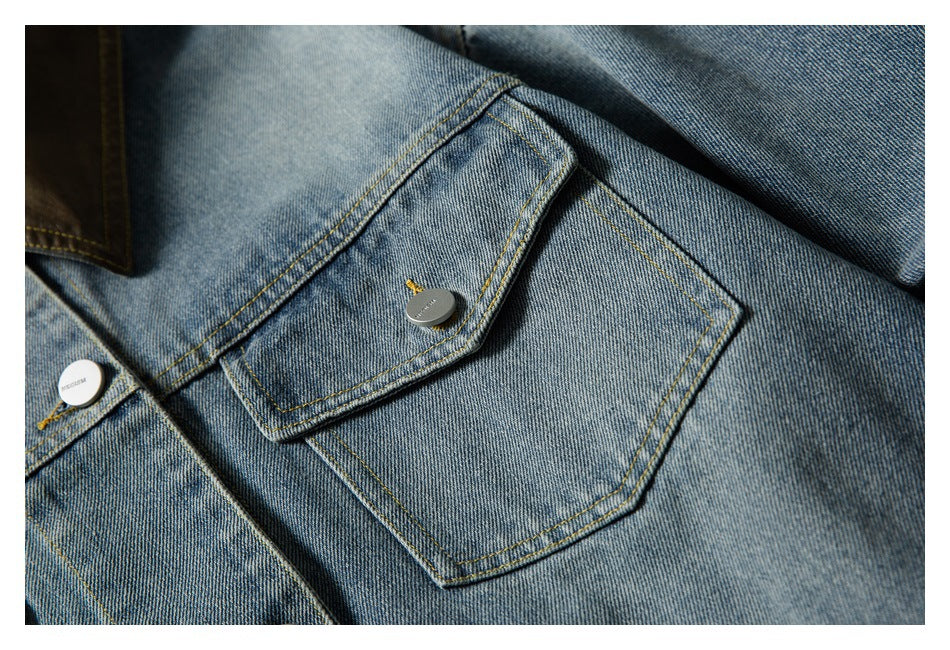 Close-up of a denim jacket's buttoned chest pocket and faded blue fabric with yellow stitching.