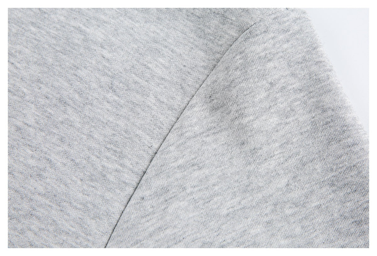 Close-up of light gray heathered knit fabric with a diagonal seam.