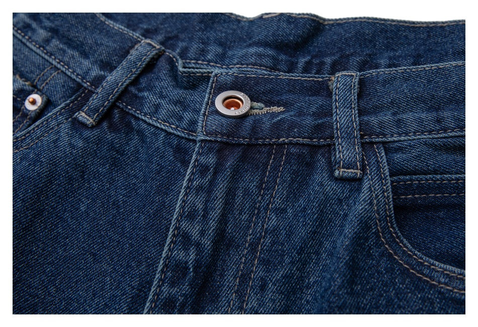 Close-up of dark blue jeans showing the front waistband button and belt loops.