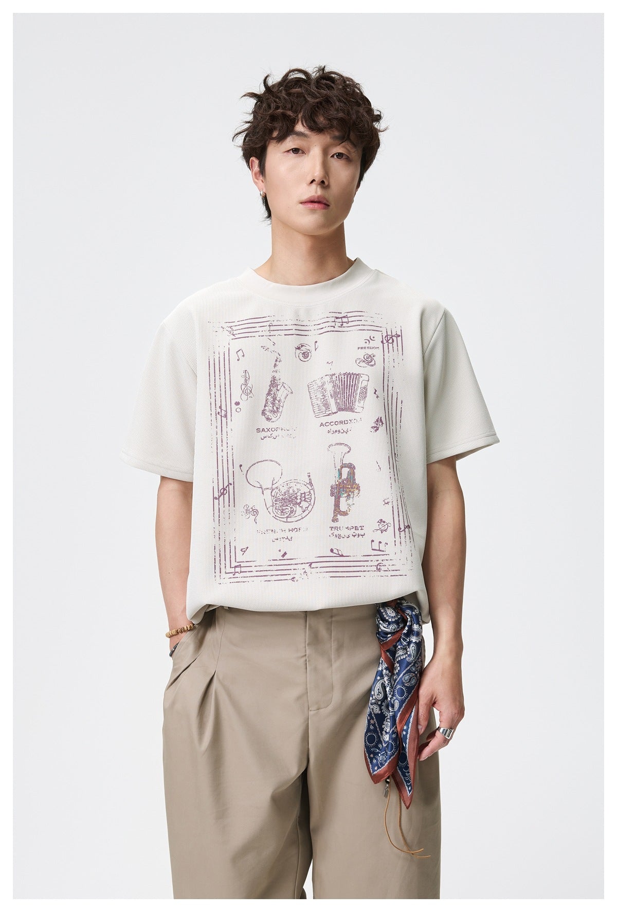 Model wearing an ivory short-sleeve T-shirt with a large vintage-style musical instrument graphic.