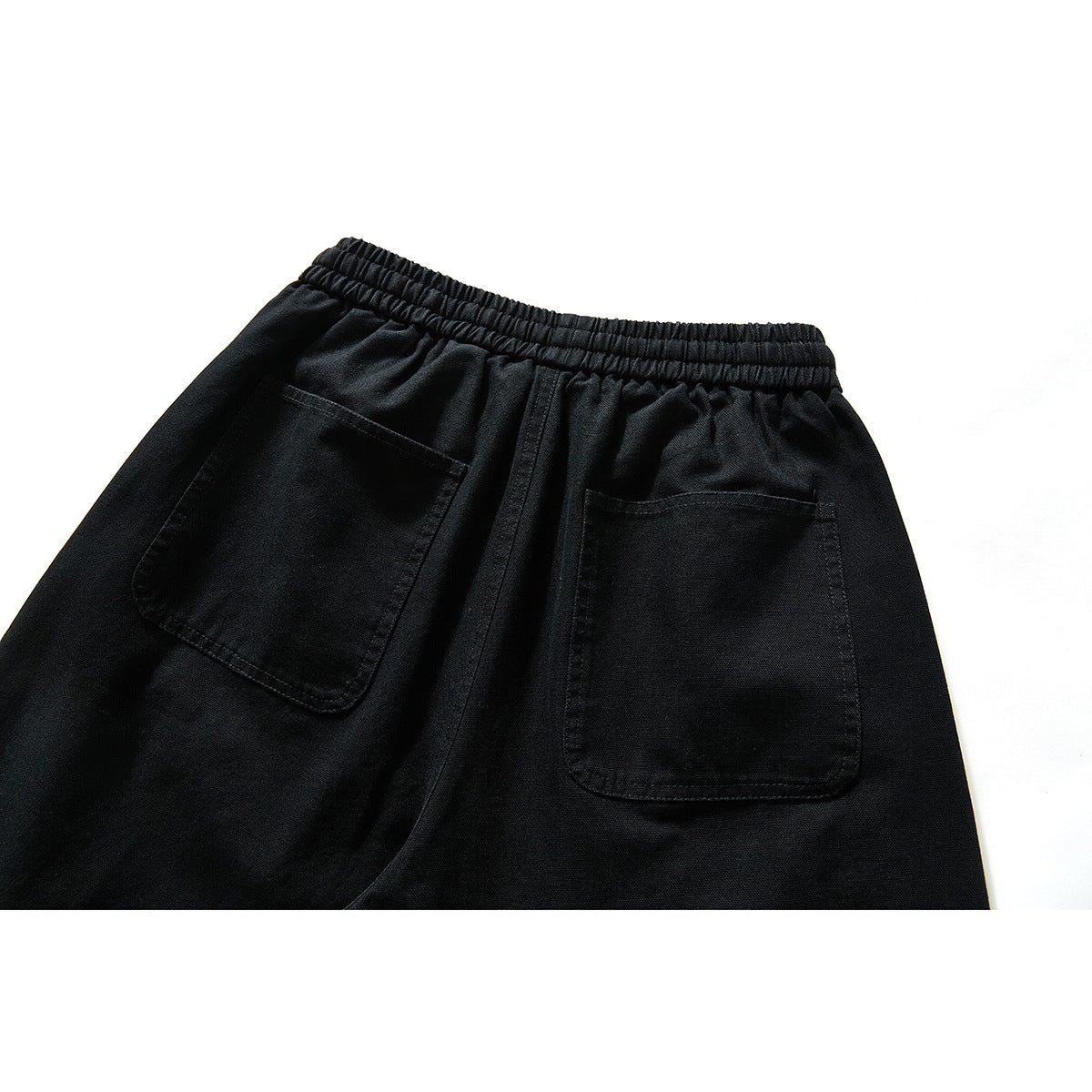 Close-up of black pants from the back, showing an elastic waistband and two large patch pockets.
