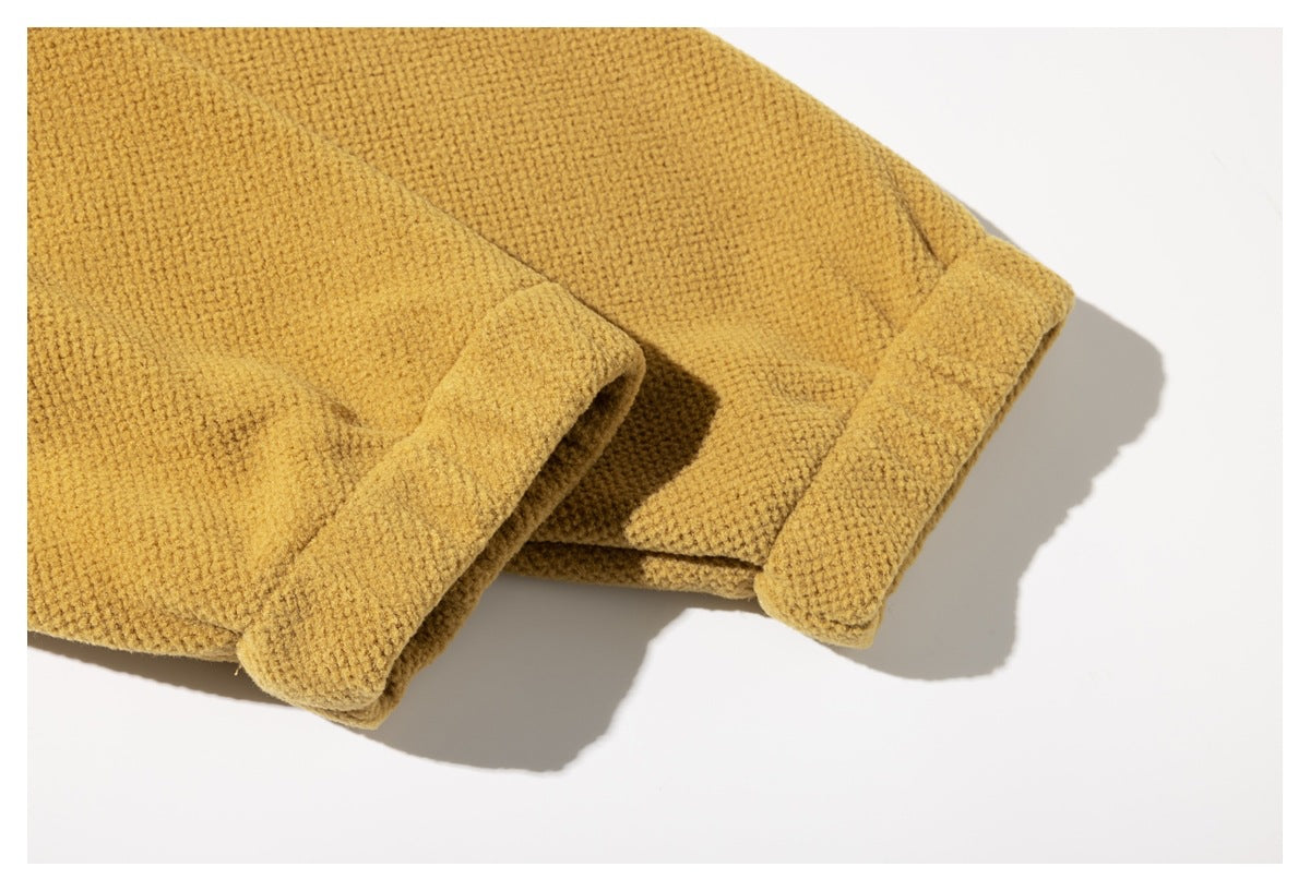 Close-up of two mustard-yellow garment edges with thick folded hems on a white background.