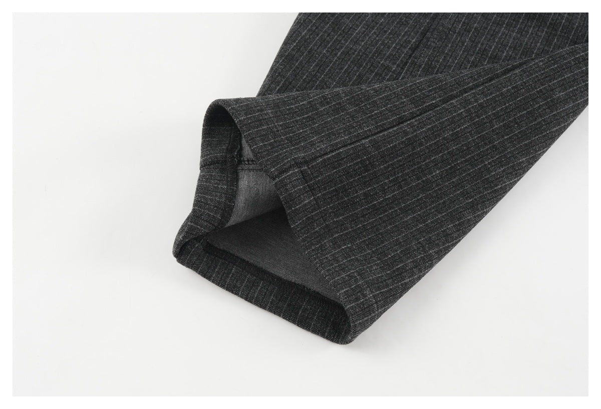 Close-up of a charcoal pinstripe trouser hem, folded back to show the inner stitching.