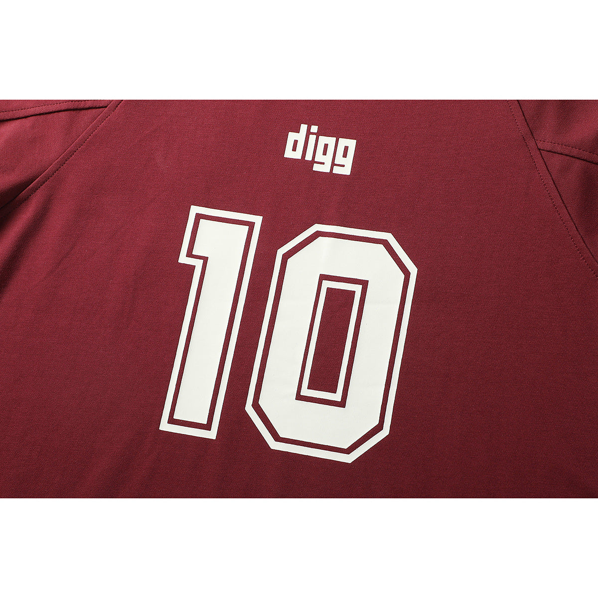 Close-up of a burgundy shirt back showing white “digg” lettering above a large outlined number 10.