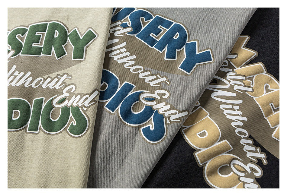 Close-up of graphic T-shirts in cream, gray, and black colorways with contrasting lettering.